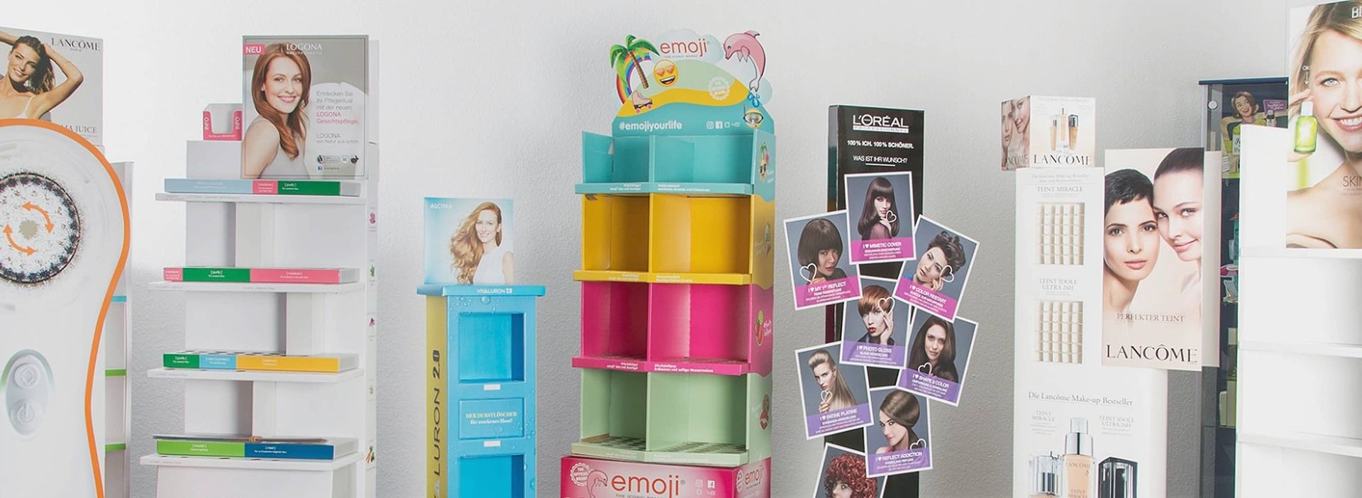 Eine Ausstellung von Schönheitsprodukten mit bunten Regalen und Werbeständern von verschiedenen Marken wie L'Oréal und Lancôme.